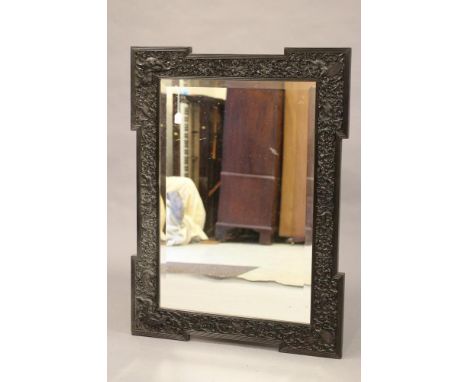 AN INDIAN CARVED EBONY(?) FRAME, c.1900, of earred oblong form profusely carved with birds and animals amongst flowers and sc