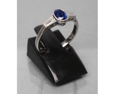 A CEYLON SAPPHIRE AND DIAMOND RING, the oval facet cut sapphire of 1.26cts collet set to angular shoulders each set with an a