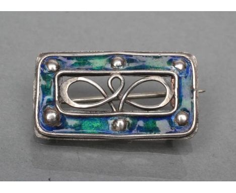 AN ARTS AND CRAFTS BROOCH, the open oblong panel with blue/green enamelling and plain bosses enclosing an open scroll centre,