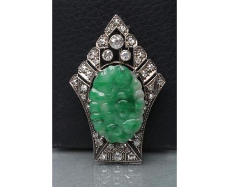 AN ART DECO JADE AND DIAMOND BROOCH, the oval green jade panel carved with fruits and claw set to a fan shaped open frame var