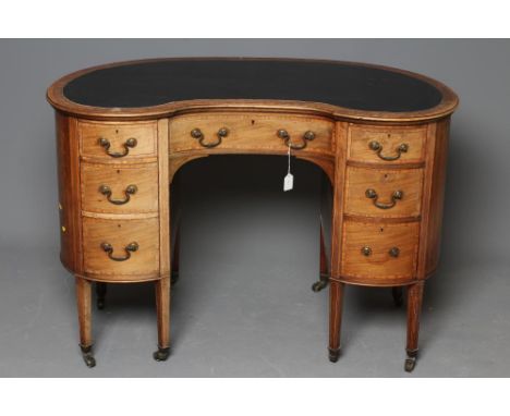 A LATE VICTORIAN DESK of kidney form, crossbanded with stringing, the moulded edged top lined in green leather, frieze drawer