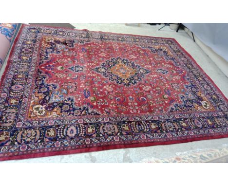 A PERSIAN CARPET, the claret field with floral sprays with navy and tangerine central gul and matching spandrels, navy blue m