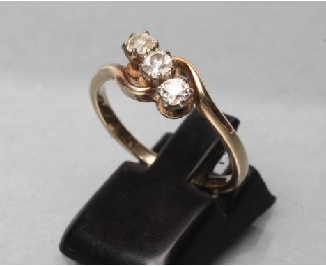 A THREE STONE DIAMOND CROSSOVER RING, the old cut stones claw set to a plain shank stamped 18ct, size P (Est. plus 21% premiu