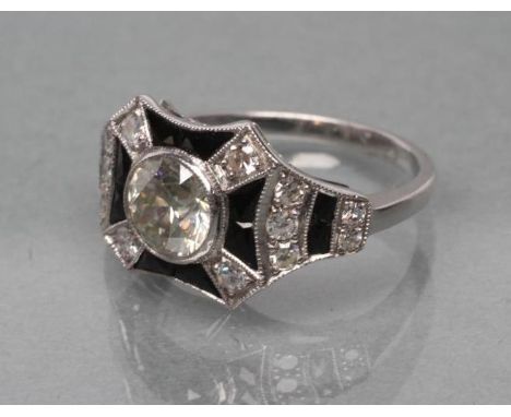 AN ART DECO DIAMOND AND ONYX COCKTAIL RING, the old brilliant cut stone of approximately 1ct, open back collet set to pave se