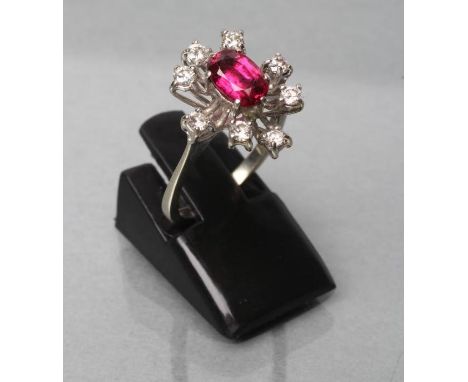 A RUBY AND DIAMOND DRESS RING, the oval facet cut ruby claw set to a star border of eight small old brilliant cut diamonds to