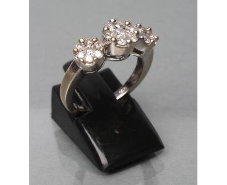 A DIAMOND TRIPLE CLUSTER RING, the central seven stone cluster point set and flanked by a pair of similar smaller clusters to