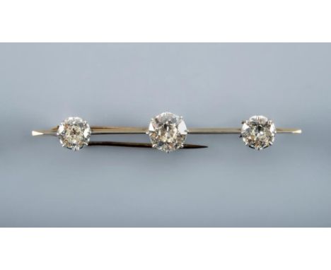 A DIAMOND BAR BROOCH, the unmarked knife edge bar centred by an old cut stone of approximately 1.75cts flanked by two similar