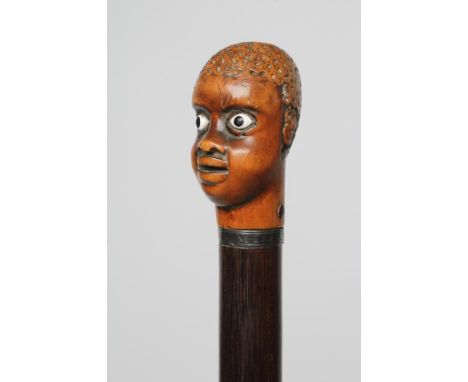 A GENTLEMAN'S WALKING STICK, early 19th century, the pommel carved as the head of a man with white glass eyes, fixed to a met