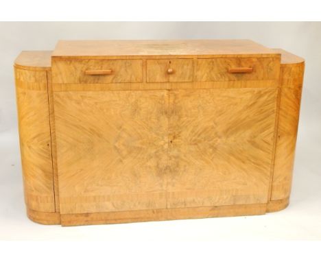 An Art Deco walnut and cross banded bow front sideboard, with three frieze drawers above cupboards, flanked by demi lune side