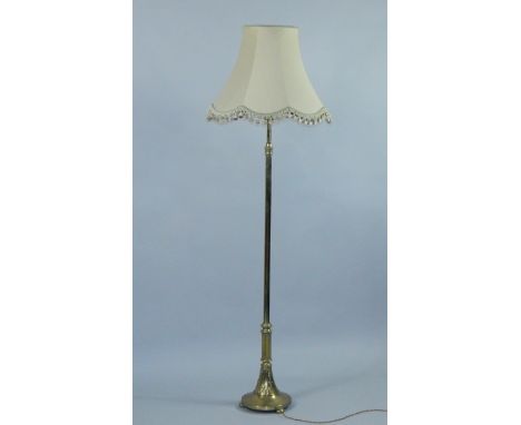 An Edwardian brass standard lamp, plain column, semi fluted at the bottom, on an outswept base and bun feet, 179cm high inclu