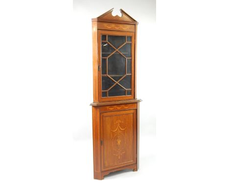 An Edwardian mahogany corner display cabinet, with satinwood cross banding and inlaid with swags and a basket of flowers, the