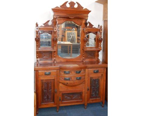 A Victorian walnut sideboard, the broken arch pediment above a triple bevelled mirrored back and super structure of shelves, 