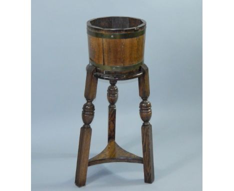 Three oak and brass bound jardinieres, two on stands, one on an sperate triform base, 95cm high, another by R A Lister on an 