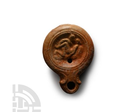 1st century A.D. Squat mould-made oil lamp with a low-relief erotic scene of two lovers; ribbed shoulder and recessed discus,