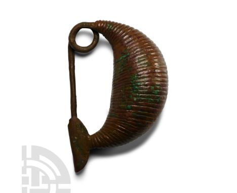 Italic, 7th century B.C. A 'sanguisuga' (leech) fibula with hollow, vertically ribbed bow; integral coiled spring and ellipso