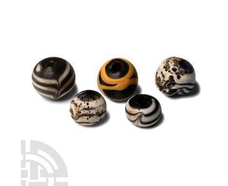 Circa 5th-7th century A.D. Mainly black glass barrel-shaped beads with white marvered trails.  8.92 grams total, 10-13 mm (3/