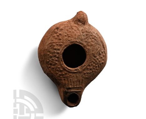 5th-6th century A.D. Squat in profile with stub handle and short nozzle, raised undulating line to discus with pellets in the