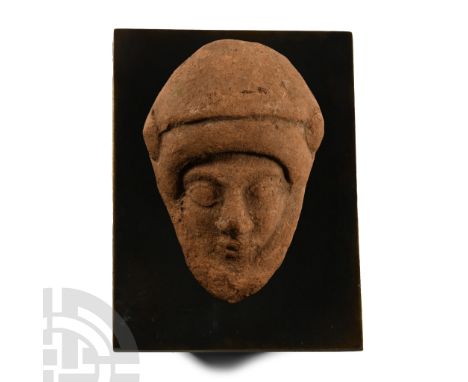 6th-5th century B.C. Modelled in the half-round with stylised facial features and wearing a large helmet; mounted on a custom