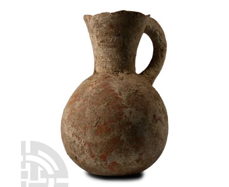 1st millennium B.C. Finely moulded reddish-orange pitcher with a wide, globular body, funicular neck and mouth, single handle