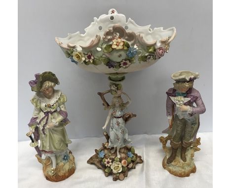 A continental pottery floral decorated centre piece of a lady figure stand with bowl top 37cm and a pair of bisque painted fi