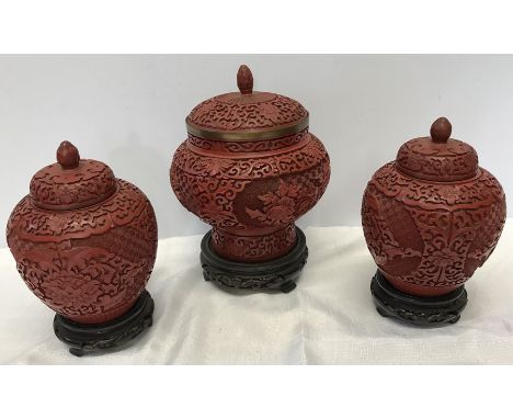 A pair and one large oriental carved cinnabar lacquer lidded jars on stands with blue enamel interior. Tall jar 22cm includin