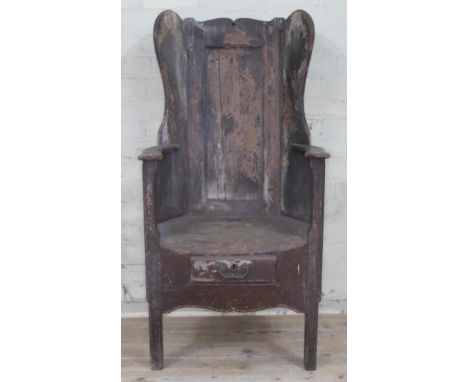 A West Lancashire three leg pine lambing chair, late 18th century with shaped, wing and panelled back, shaped arms, lower dra