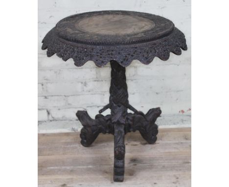 A 19th century Anglo-Indian rosewood tripod table with flip top and carved profusely with hunting scenes, diam. 67cm &amp; he