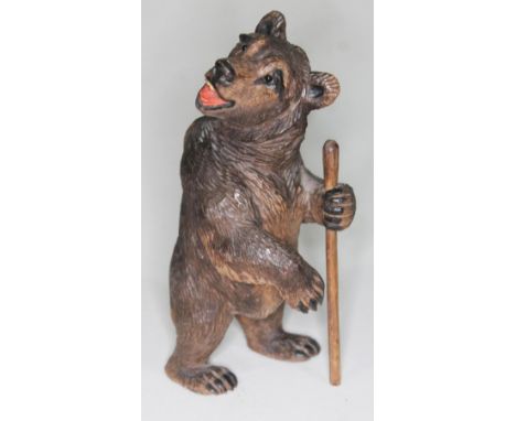 A Black Forest carved wooden bear holding a walking stick, height 14.5cm.  