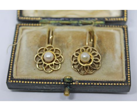 A pair of yellow metal earrings, each formed as an open work flower and set with a central cultured pearl, diam. 14mm, unmark