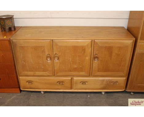 A light Ercol sideboard, enclosed by three doors fitted two drawers below, raised on shepherd castors, 129cm wide x 44cm deep