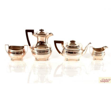 A George V silver four piece tea set, having reeded body decoration raised on ball feet, the hot water jug and tea pot with b