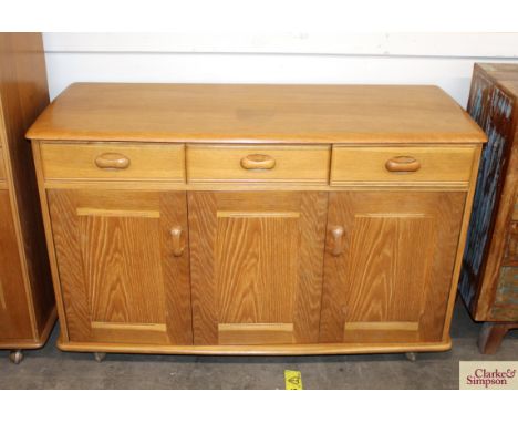 An Ercol style light wood sideboard fitted three drawers and cupboards below raised on shepherd castors, 119cm wide x 48cm de