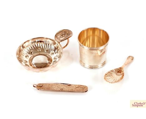 A small  Tiffany &amp; Co. Sterling beaker; a silver shell shaped caddy spoon; a white metal wine taster inscribed "Millie"; 