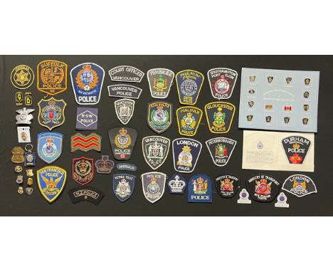A collection of Canadian and US Police shoulder sleeve insignia and enamel badges. Also some Commonwealth Police Force insign