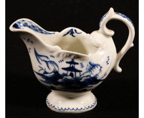 18th century Derby butter boat of miniature shell shape with a scroll handle and feather rim and blue and white decoration of