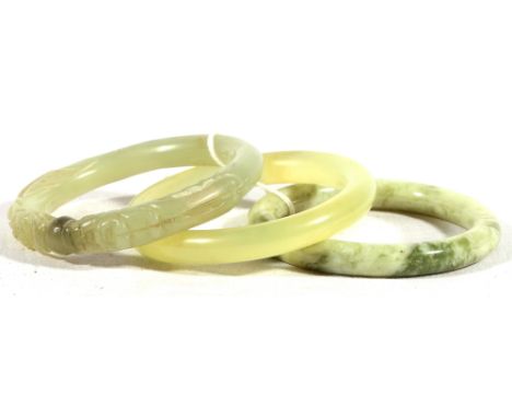 Chinese 20th Century jade bangle carved with two dragons and a flaming pearl and two others. (3)