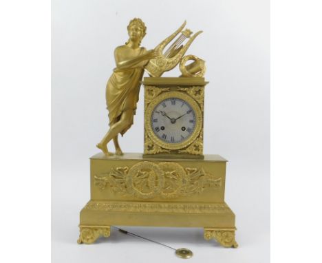 An early 19thC French ormolu mantel clock, with a lyre playing figure leaning to a silvered dial over a frieze with laurels a