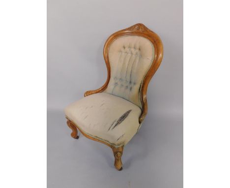 A Victorian walnut spoon back nursing chair, with overstuffed seat and button back, raised on cabriole legs, on castors.