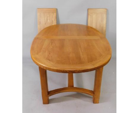 A light oak oval extending dining table, with two additional leaves, raised on chamfered square legs united by a L frame stre