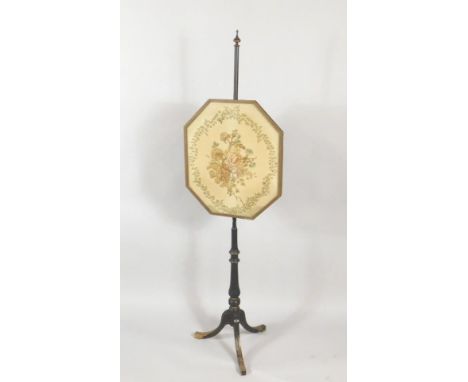 An early 19thC ebonised pole screen, the octagonal shaped banner with a crewelwork panel of flowers and leaves, on a turned c