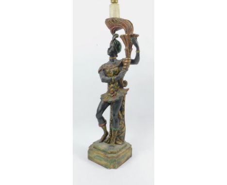 A gilt and painted plaster blackamoor table lamp modelled standing, raised on a coated square base, 72cm high.