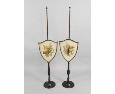 A pair of late 19th/early 20thC mahogany pole screens, each with a shield shaped banner inset with an earlier silk crewelwork