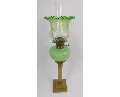 A late 19thC brass Corinthian column oil lamp, with an acanthus moulded green moulded glass reservoir and a green to clear mo