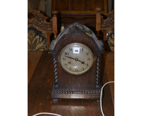 An early 20th Century mantel clock in dark stained arch-shaped case, with decorative spiral twist columns and a silver plaque