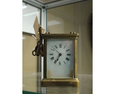 A brass carriage clock with white enamel dial and roman numerals, the plaque to the reverse inscribed 'R. & Co., Made in Pari