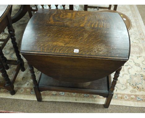 An oak trolley table with shelf under, raised on turned bottom supports.