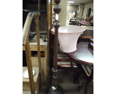 A mahogany standard lamp on a turned and reeded column, fitted a pink shade.