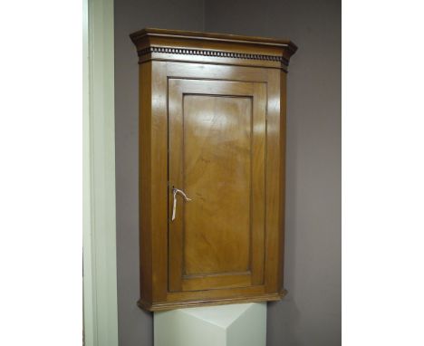 A mahogany wall hanging corner cupboard, with flared dentil cornice above a single door enclosing a shaped shelf.