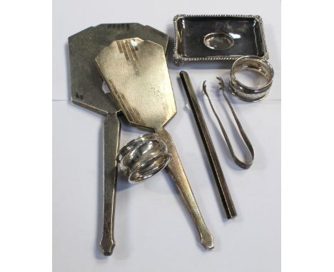 Two hallmarked silver napkin rings, a pair of silver sugar tongs, a small white metal rectangular dish with paw feet, a hallm