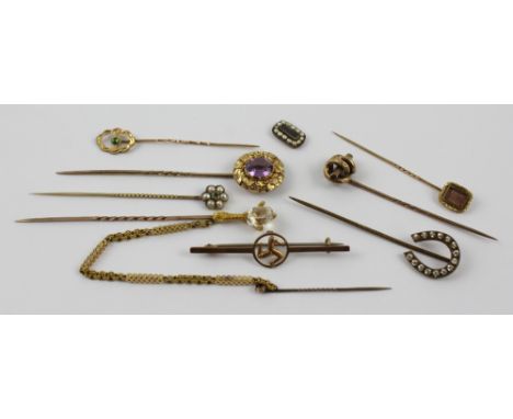 A small collection of gold and yellow metal stick pins to include a knotwork example, horseshoe example, one set with peridot